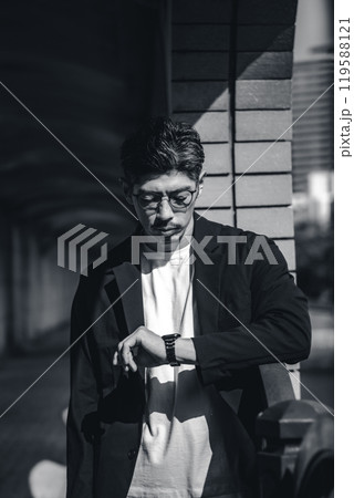 待ち合わせ中に時計を見るメガネをかけた男性 待ち合わせ中に時計を見るメガネをかけた男性 119588121