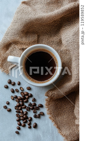 Warm cup of brewed coffee beside scattered coffee beans and a sealed package in a cozy setting 119589852