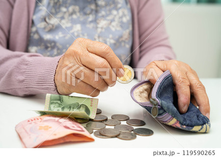 Asian senior or elderly old lady woman holding counting coin money in bag. Poverty, saving problem in retirement. Asian senior or elderly old lady woman holding counting coin money in bag. Poverty, saving problem in retirement. 119590265
