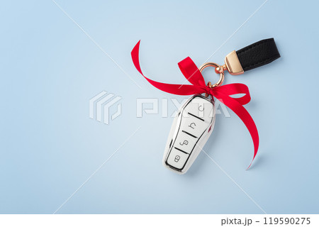Car key with red bow ribbon on blue background, top view Car key with red bow ribbon on blue background, top view 119590275