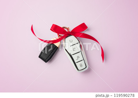 Car key with red bow ribbon on pink background Car key with red bow ribbon on pink background 119590278