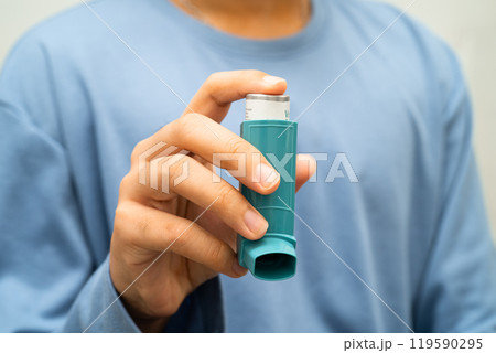 Asthma and chronic obstructive pulmonary disease COPD, Asian young man using metered dose inhaler MDI. Asthma and chronic obstructive pulmonary disease COPD, Asian young man using metered dose inhaler MDI. 119590295