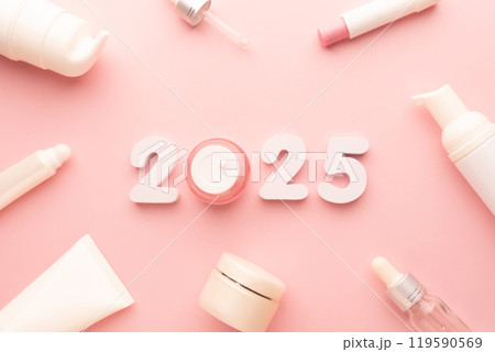 Best skincare products and cosmetic trends of 2025 concept. 2025 white number with lip balm, cream bottle, serum and lotion on pink background. Best skincare products and cosmetic trends of 2025 concept. 2025 white number with lip balm, cream bottle, serum and lotion on pink background. 119590569