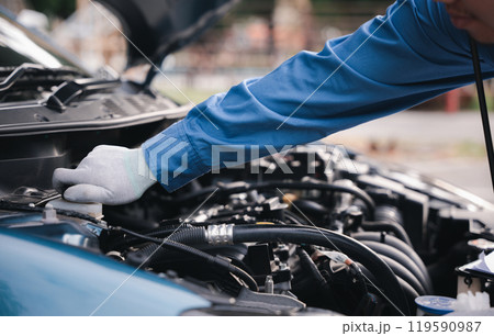 Auto mechanic writing on a clipboard checking car engine at workshop. Expertise in car service and repair technology-driven. Technician ensuring safety smiling at the challenge. Auto mechanic writing on a clipboard checking car engine at workshop. Expertise in car service and repair technology-driven. Technician ensuring safety smiling at the challenge. 119590987