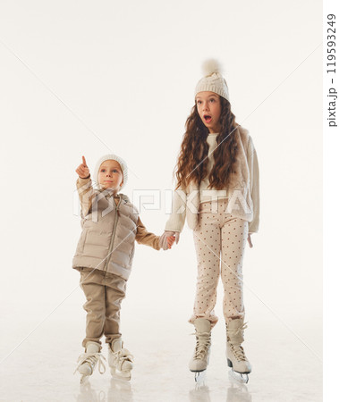 Kids spot something exciting as they continue their skating fun, filled with wonder and holiday spirit against white studio background. Kids spot something exciting as they continue their skating fun, filled with wonder and holiday spirit against white studio background. 119593249