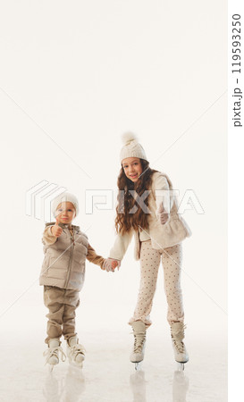 Thumbs up from kids, excited and proud of their ice-skating fun during the winter family holiday against white studio background. 119593250