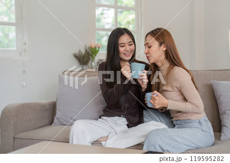 Lesbian and LGBT Couple Enjoying Coffee Together at Home in a Cozy and Modern Living Room Setting Lesbian and LGBT Couple Enjoying Coffee Together at Home in a Cozy and Modern Living Room Setting 119595282