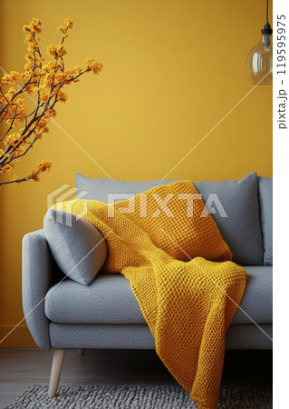 Cozy living room with a grey sofa and vibrant yellow blanket against a sunny yellow wall Cozy living room with a grey sofa and vibrant yellow blanket against a sunny yellow wall 119595975