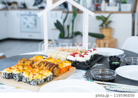 Set of sushi and rolls on the table at home In the white kitchen with a figurine of a house Set of sushi and rolls on the table at home In the white kitchen with a figurine of a house 119596856
