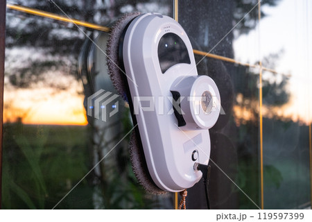 A window cleaner robot cleans windows in a house from the outside. Cleaning assistant, safe window cleaning, remote control A window cleaner robot cleans windows in a house from the outside. Cleaning assistant, safe window cleaning, remote control 119597399