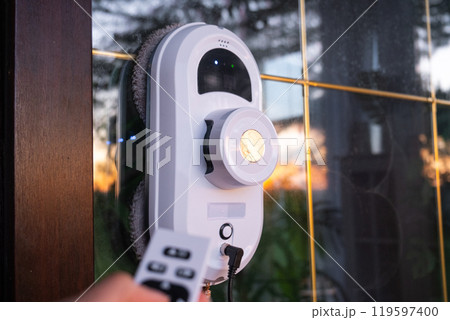 A window cleaner robot cleans windows in a house from the outside. Cleaning assistant, safe window cleaning, remote control A window cleaner robot cleans windows in a house from the outside. Cleaning assistant, safe window cleaning, remote control 119597400