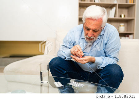 Middle aged senior man with medical pill and glass of water. Mature old senior grandfather taking medication cure pills vitamin. Age prescription medicine healthcare therapy concept Middle aged senior man with medical pill and glass of water. Mature old senior grandfather taking medication cure pills vitamin. Age prescription medicine healthcare therapy concept 119598013