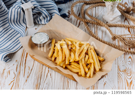 Golden French fries with a side of creamy dip, perfect for snack lovers 119598565