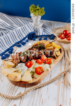 Mixed grill platter with skewers, roasted potatoes, pita, salad, and tzatziki, meal combination 119598568