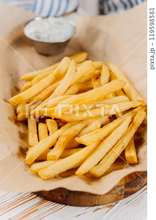 Golden French fries with a side of creamy dip, perfect for snack lovers 119598581