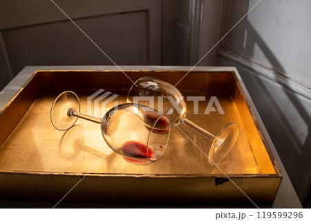 Used wine glasses, two half empty glasses of red wine on a golden tray background 119599296