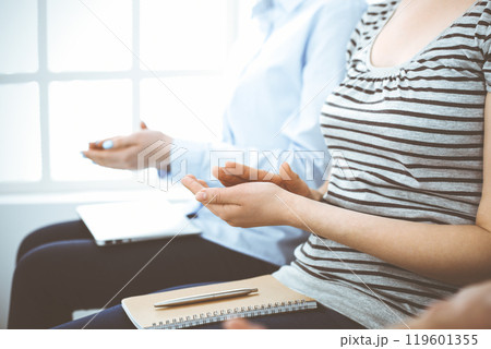 Business people clapping at meeting or conference, close-up of hands. Group of unknown businessmen and women in modern white office. Success teamwork, corporate coaching and applause concept 119601355