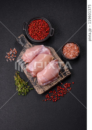 Fresh chicken fillet on a dark concrete table with spices and herbs Fresh chicken fillet on a dark concrete table with spices and herbs 119601375