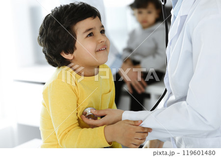 Woman-doctor examining a child patient by stethoscope. Cute arab boy at physician appointment. Medicine help concept 119601480