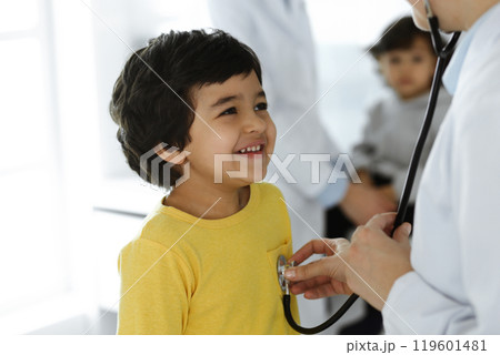 Woman-doctor examining a child patient by stethoscope. Cute arab boy at physician appointment. Medicine help concept 119601481