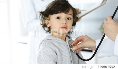 Woman-doctor examining a child patient by stethoscope. Cute arab toddler at physician appointment. Medicine concept Woman-doctor examining a child patient by stethoscope. Cute arab toddler at physician appointment. Medicine concept 119601532