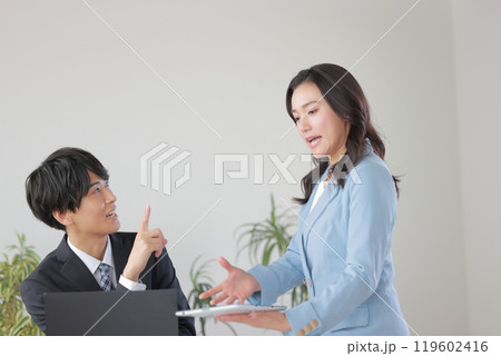 上司の質問に回答を話す部下 119602416
