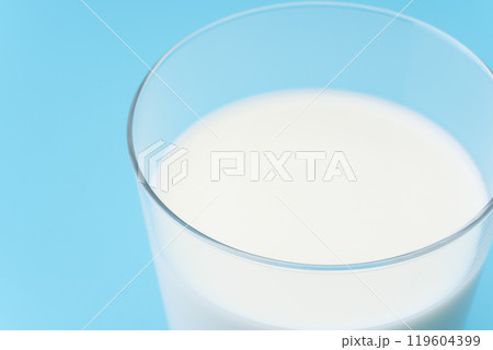 水色背景にグラスに入った牛乳のクローズアップ 119604399