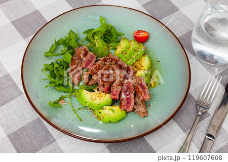 Fried beef served with avocado and herbs 119607608