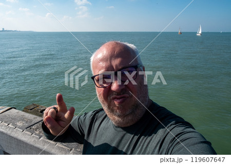 A man enjoys a beautiful seaside setting with a stunning view of the ocean and horizon A man enjoys a beautiful seaside setting with a stunning view of the ocean and horizon 119607647
