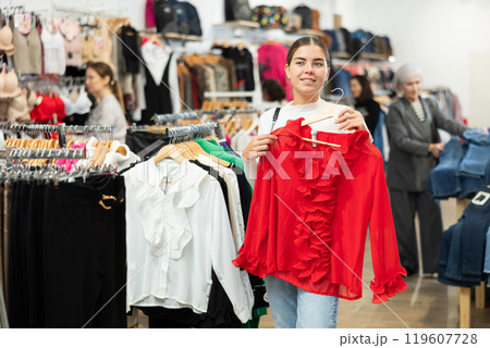Young woman choosing blouse in store 119607728