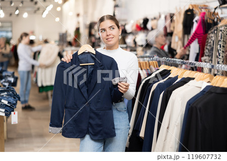 Young girl choosing convenient blazer in clothing store Young girl choosing convenient blazer in clothing store 119607732