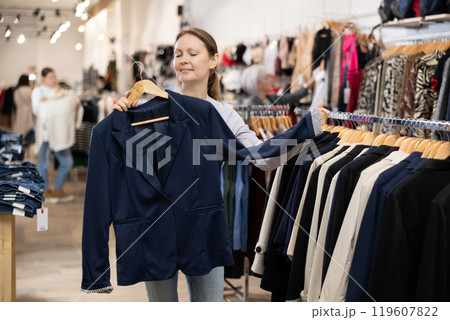Satisfied woman trying on a new jacket in clothing boutique Satisfied woman trying on a new jacket in clothing boutique 119607822