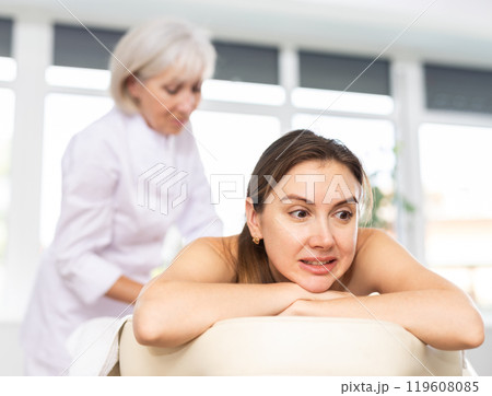 Young woman suffers painful sensations and winces during therapeutic massage session 119608085