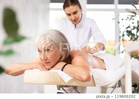 Elderly woman enjoying massage from professional female masseur Elderly woman enjoying massage from professional female masseur 119608202