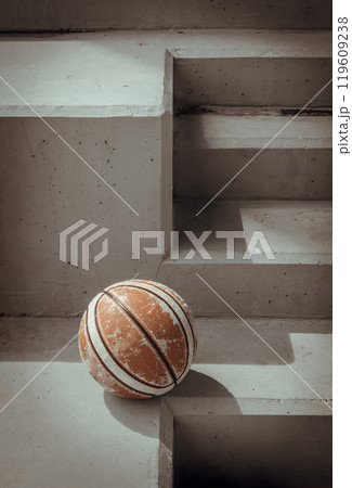 Old basketball ball on cement floor with Stairs leading and Natural light. Old basketball ball on cement floor with Stairs leading and Natural light. 119609238