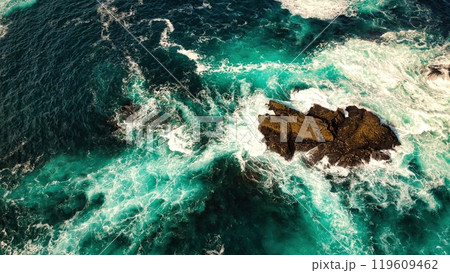 Stunning Aerial View of Vibrant Turquoise Waves Elegantly Crashing Against Rocky Shoreline Stunning Aerial View of Vibrant Turquoise Waves Elegantly Crashing Against Rocky Shoreline 119609462