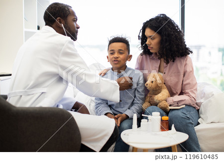 Doctor examining young boy with mother by his side in hospital room 119610485