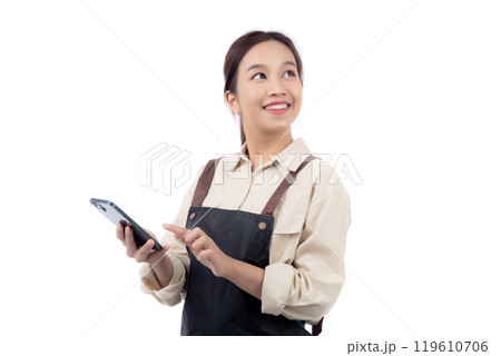 Portrait happy young asian barista woman in apron smiling while looking smart phone isolated. 119610706
