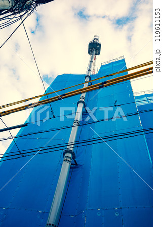 街中で建設中のマンションと高く伸びるタワークレーン 暖色 街中で建設中のマンションと高く伸びるタワークレーン 暖色 119611153