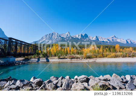 Canadian Rockies autumn landscape. Mount Rundle mountain range and trees reflected on the Bow River. Canmore, Alberta, Canada. Canmore Engine Bridge. 119613266