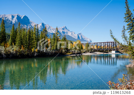 Canadian Rockies autumn landscape. Mount Rundle mountain range and trees reflected on the Bow River. Canmore, Alberta, Canada. Canmore Engine Bridge. 119613268