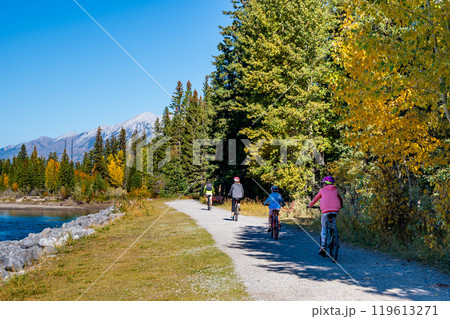 People cycling along the Bow River walking trail in autumn. Canmore, Alberta, Canada. Higashikawa Friendship Trail. People cycling along the Bow River walking trail in autumn. Canmore, Alberta, Canada. Higashikawa Friendship Trail. 119613271