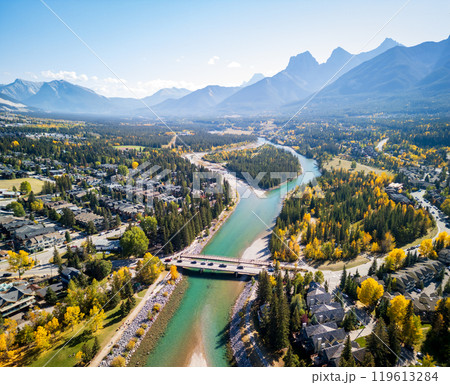 Aerial view of Town of Canmore residential area and Bow River in autumn sunny day. Canadian Rockies mountain range in background. Alberta, Canada. Aerial view of Town of Canmore residential area and Bow River in autumn sunny day. Canadian Rockies mountain range in background. Alberta, Canada. 119613284