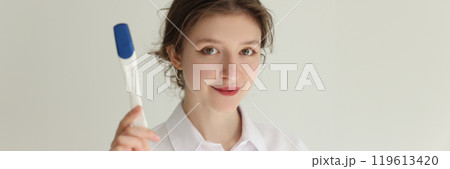 Smiling young brunette woman shows electronic thermometer Smiling young brunette woman shows electronic thermometer 119613420