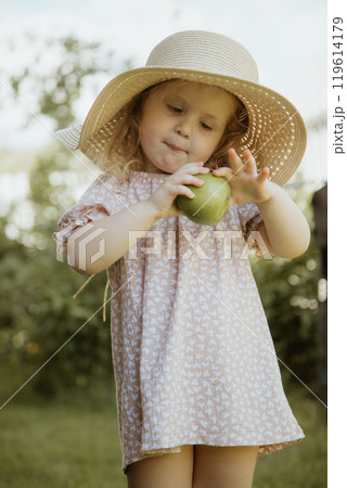 Joyful Girl in a Dress and Straw Hat, Holding an 119614179