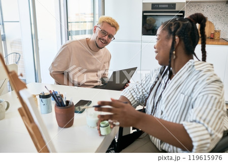 Multiracial colleagues enjoying productive brainstorming session in modern office space with laptops and supplies spread on the table, sharing ideas and insights 119615976