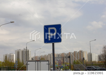 A blue parking sign stands against a backdrop of residential buildings, indicating the availability of parking spaces in the city. A sign permitting parking on city streets. 119615991