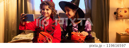 Kids in costumes taking selfie on bed 119616597