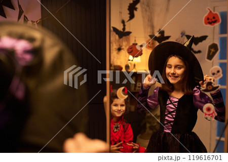 Little witch standing in front of mirror 119616701