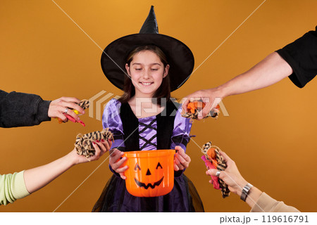 Hands putting candies into witch bucket Hands putting candies into witch bucket 119616791
